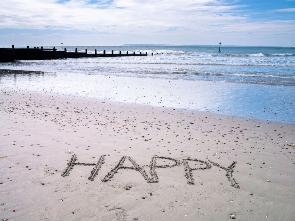 HAPPY message written in smooth sand at the beach