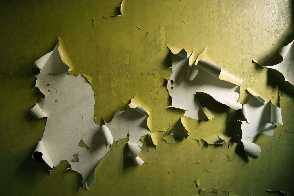 Afladderende Verf op Groene Muur