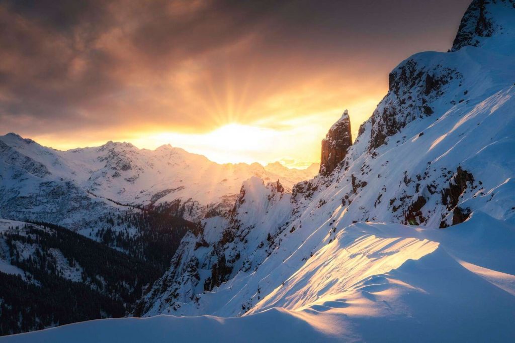 Avondzon achter besneeuwde bergtoppen