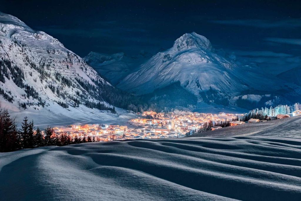 Winterdorp onder maanlicht in alpenvallei
