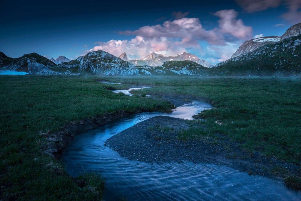 Avondlicht over bergvallei met beek