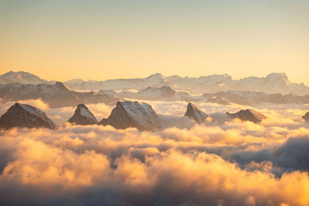 Bergpieken boven gouden wolkenzee