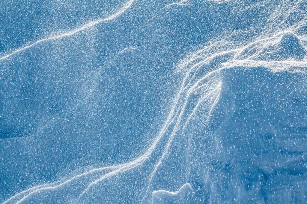 Wervelende sneeuw op ijsblauw landschap