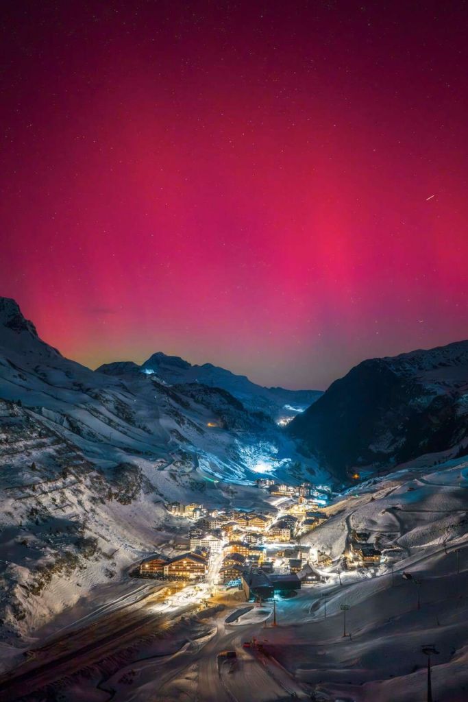 Roze noorderlicht boven bergdorp