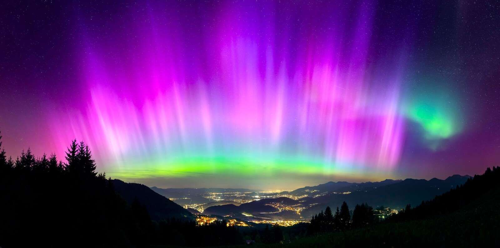 Noorderlicht boven verlichte bergstad