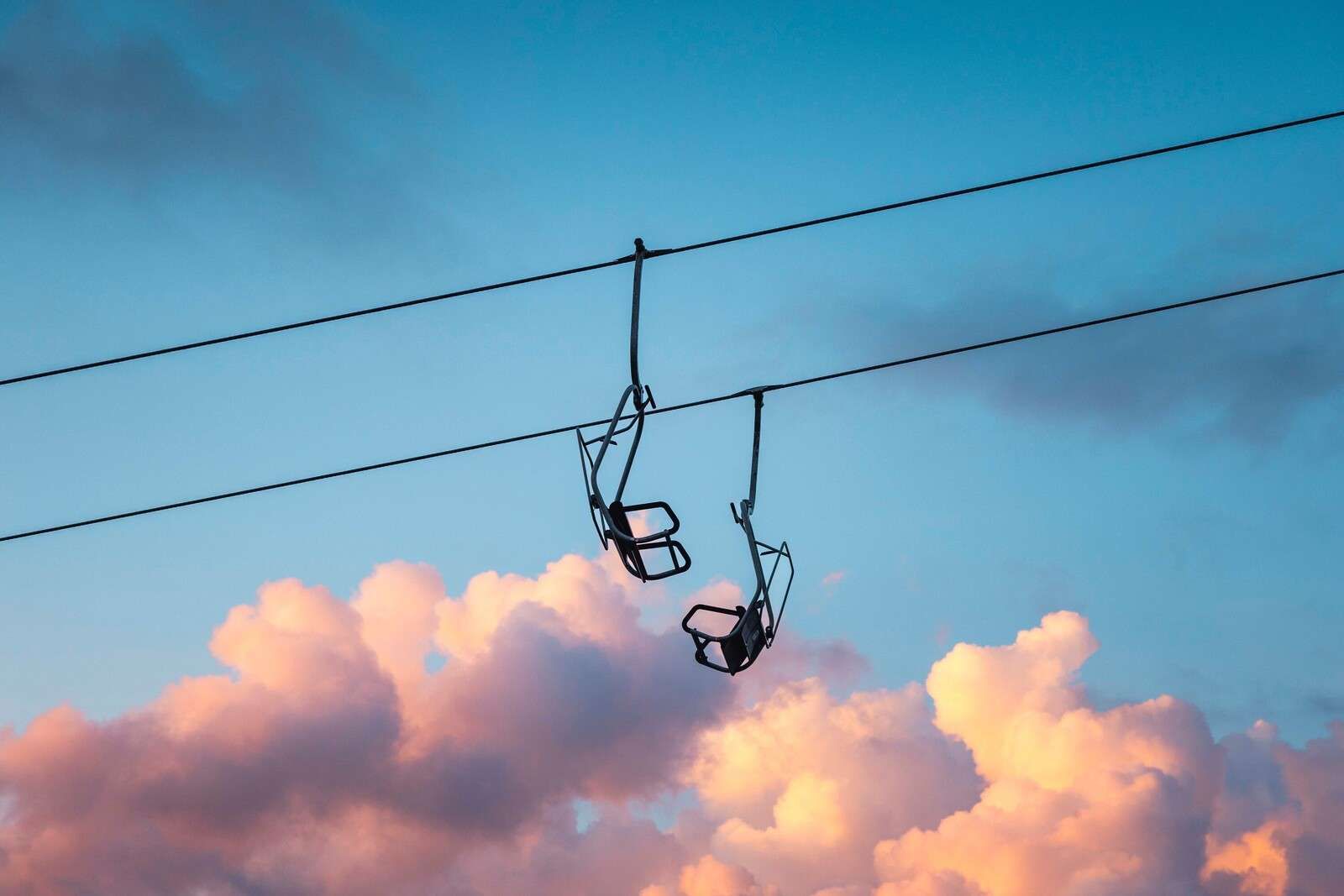 Stoeltjeslift boven roze avondwolken