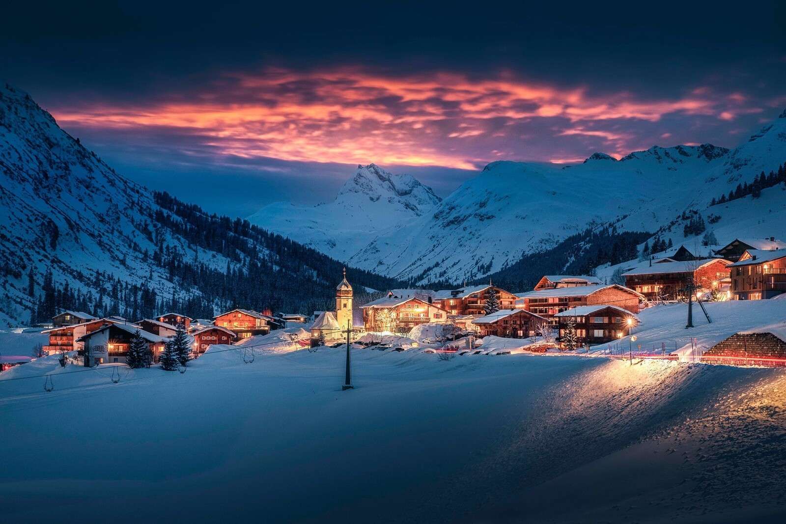Avondlicht over bergdorp in de sneeuw