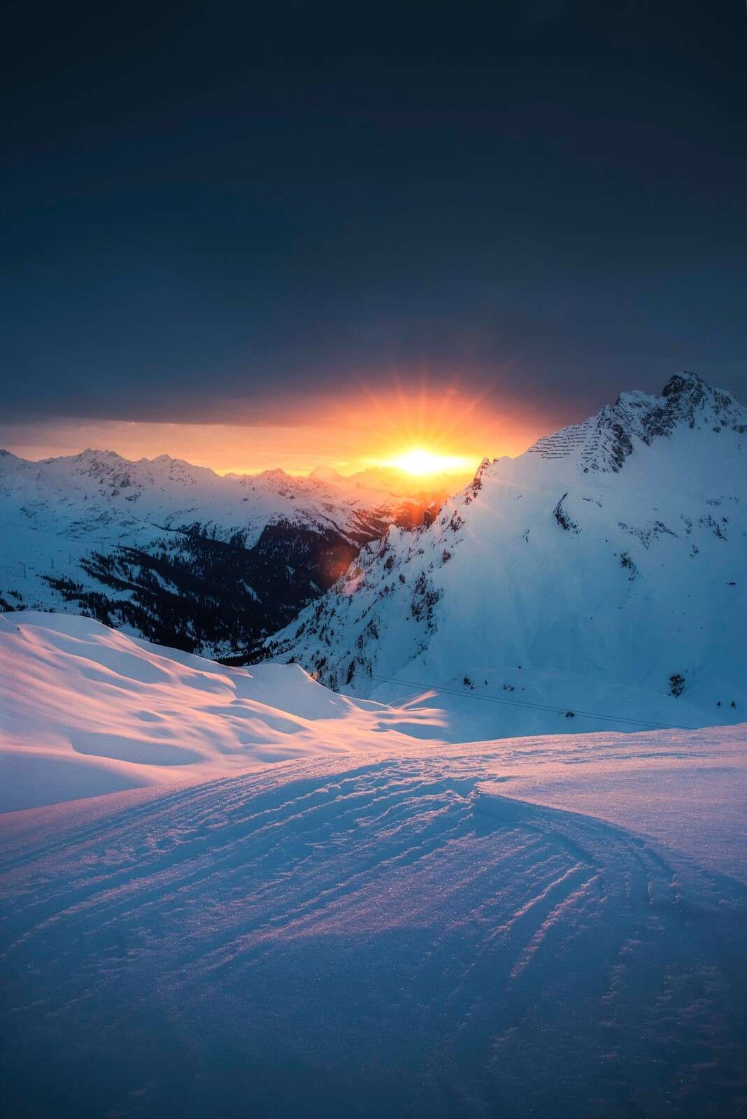 Ondergaande zon boven besneeuwde alpentoppen