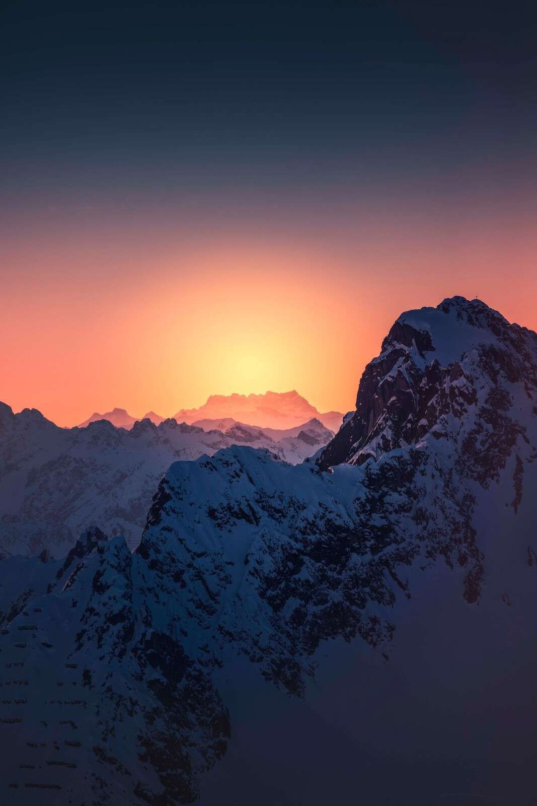 Besneeuwde bergtop bij vurige zonsopkomst